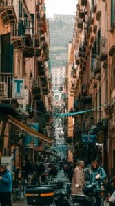 Una stretta strada di Napoli con edifici alti e persone che camminano